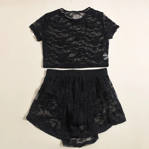 Gedetailleerde close-up van zwart bloemenkant op de tweedelige crop top en rok combinatie