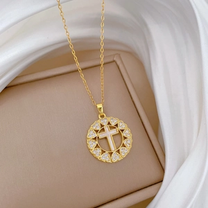 Macro shot of gold cross necklace with heart-shaped diamond pavé detail on silk
