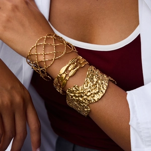 Gold hammered cuff bracelet and hollow mesh bangle set on model wrist with white shirt