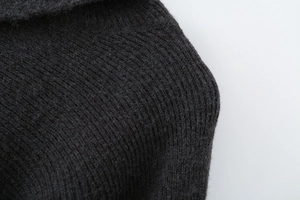 Close-up detail of dark grey knit texture with soft wool cashmere fibers on cape sweater