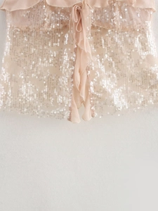 Detail of pink sequin camisole featuring ruffle hem and adjustable drawstring ties