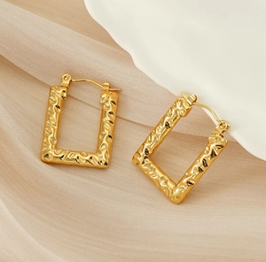 Macro shot of 18K gold plated hoop earrings with molten lava texture on fabric