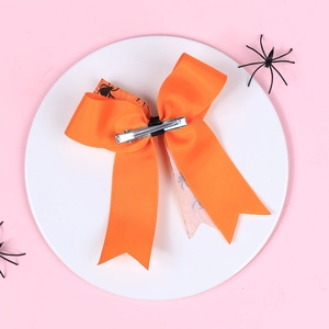 Detail of orange Halloween bow hair clip with spider patterns and metal duckbill clip