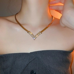 Detail of gold-plated V-shaped necklace with sparkling crystals on a flat snake chain