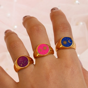Tre anelli dorati con smalto viola, rosa e blu con motivi di stelle e luna
