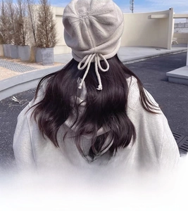 Detail of beige knitted beanie featuring a delicate decorative bow on the back view