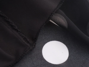 Detailed close-up of white polka dot pattern on black chiffon fabric with edge stitching