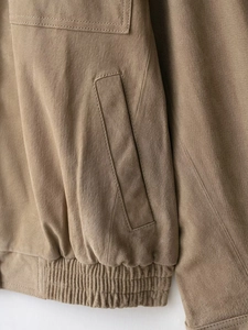 Detail view of brown suede jacket showing precision stitching and elastic ribbed hem