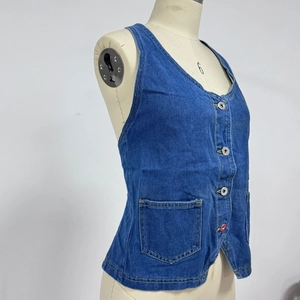 Detail view of dark blue denim vest with silver buttons and a single chest pocket