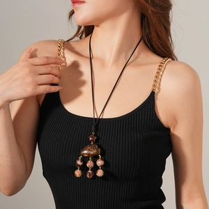Detail of a brown resin cloud pendant necklace with amber beads on a professional model