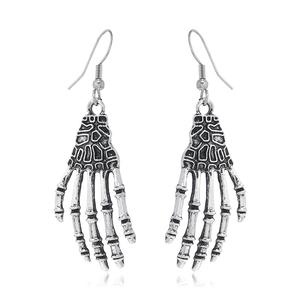 Détail de boucles d'oreilles main de squelette gothique argentées sur fond blanc