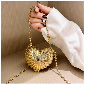 Detail of a heart-shaped golden mini bag with shell texture and beaded chain strap