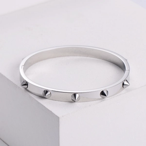 Silver punk style titanium steel rivet bangle displayed on a white geometric block pedestal