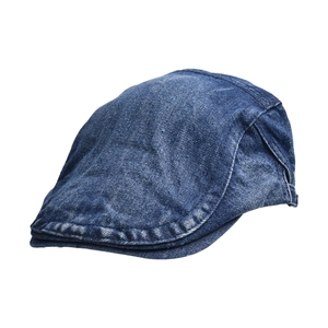 Detail of a dark blue washed denim flat cap with visible contrast stitching on white background