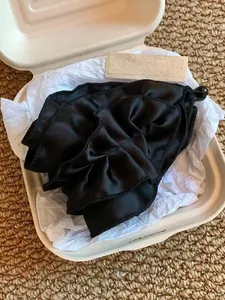 Détail d'une grande pince à cheveux en satin noir avec fleurs plissées en boîte