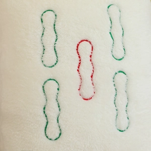 Macro detail of plush mahjong pillow fabric with green and red embroidered stripe pattern