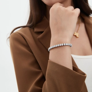 Classic silver tennis bracelet with round-cut cubic zirconia worn by a model in a suit