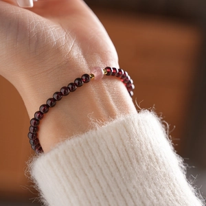 Close-up of garnet bead bracelet with pink quartz center and gold accents on wrist