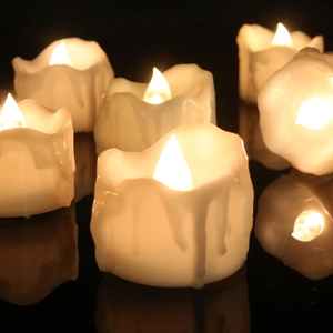 Detail of warm yellow LED candle with realistic dripping wax effect on dark background