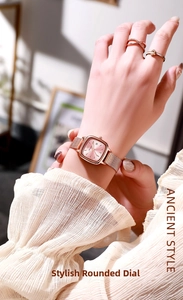 Close-up of rose gold square watch with pink dial and mesh strap on a female wrist