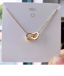 Detailed view of interconnected double heart pendant on a gold cross chain necklace