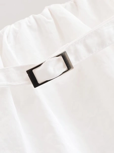 Détail du tissu blanc et de la boucle en métal poli sur le pantalon pour femmes