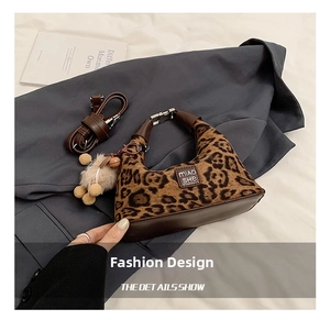 Close-up of leopard print handbag with leather base, shoulder strap and plush charm