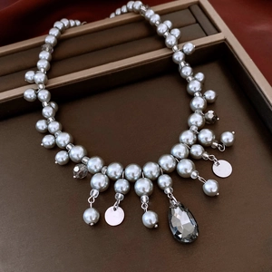 Dettaglio collana di perle di vetro grigie con pendente in cristallo su vassoio per gioielli