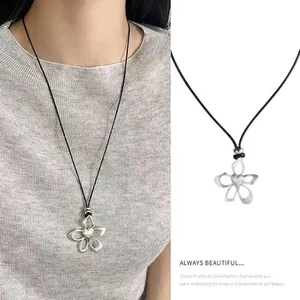 Detail of silver hollow flower pendant on adjustable black cord necklace with model view