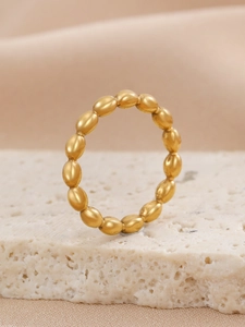 Macro shot of gold beaded stainless steel ring on natural stone showing fine metal texture