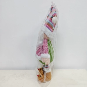 Detail of a colorful plush Christmas gnome doll in transparent packaging with striped hat