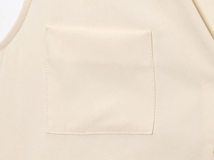 Détail du tissu en crêpe beige montrant la poche plate et les coutures de précision