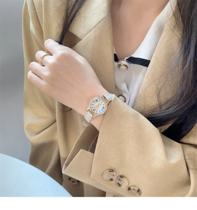 Detail of luxury gold case watch with diamond bezel and white leather strap on wrist