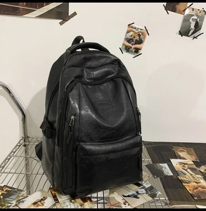 Dettaglio di un grande zaino nero in pelle PU con logo su sfondo a griglia metallica