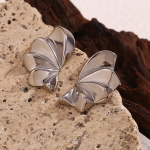 Close-up of silver geometric petal earrings on natural stone and dark wood background