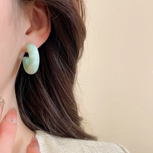 Gros plan d'un mannequin portant des boucles d'oreilles en résine en C motif marbré