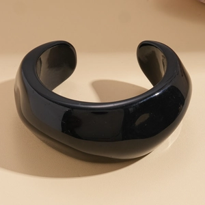 Close-up of a polished black resin open cuff bangle with a high-gloss mirror finish