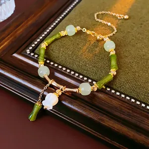 Bracelet style bambou avec perles vertes et charm de fleur de muguet blanche