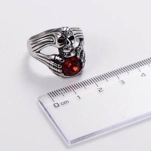 Detailed scale view of a silver gothic skull ring featuring a faceted red gemstone inlay