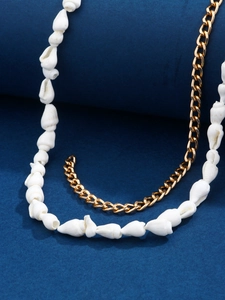 Detail of seashell and gold link chain necklace on blue velvet for beach wear