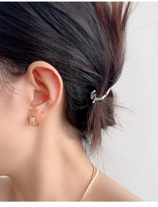 Detail of gold micro-pave hoop earrings and silver twisted hair clip on model
