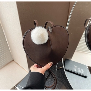 Detail einer braunen herzförmigen Wildledertasche mit großem weißem Kunstpelz-Bommel