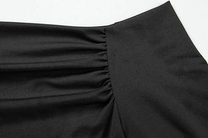 Detailed view of elegant ruched fabric texture on a slim fit black off-shoulder top