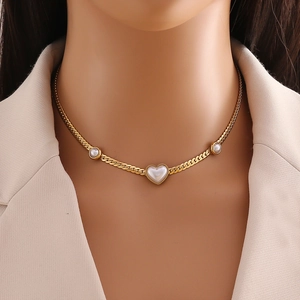 Golden stainless steel heart pearl necklace set worn by a model in a beige suit