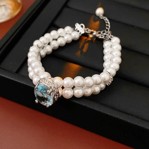 Détail d'un collier de perles double rang avec un grand pendentif ovale en gemme bleue