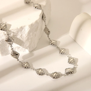 Macro shot of silver titanium steel necklace featuring textured geometric links and ocean motifs