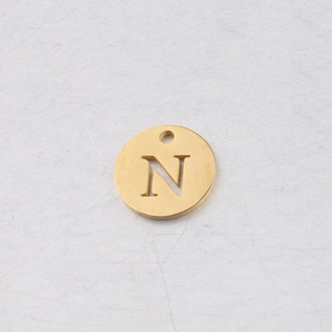 Détail macro d'un pendentif rond doré en acier inoxydable de 12 mm avec la lettre N