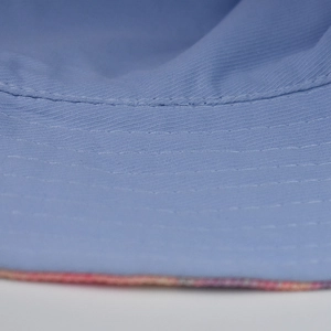 Detail of light blue tie-dye bucket hat featuring reinforced stitching and colorful trim