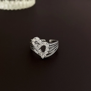 Macro shot of silver bow heart open ring with white zircon stones on leather background