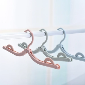Portable folding travel hangers in pastel pink, green, and blue on a metal drying rack